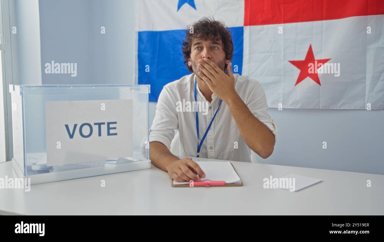 Il giovane nella sala del collegio elettorale con la bandiera panamense osserva il processo di voto Foto Stock