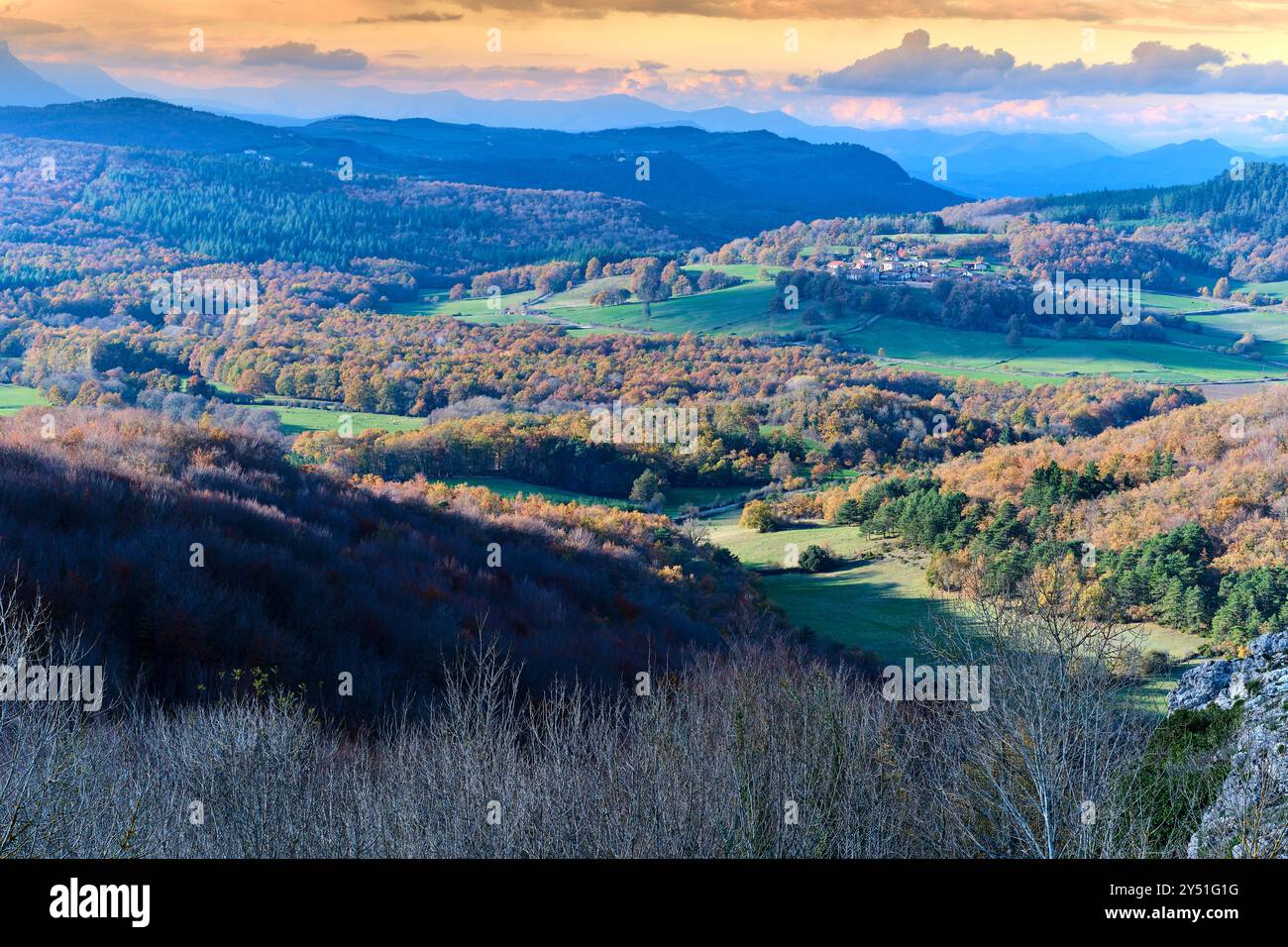 Una vista panoramica delle colline ondulate ricoperte di alberi autunnali, che si estendono in lontananza con un villaggio annidato tra i campi. Vitoriano, Araba, B. Foto Stock