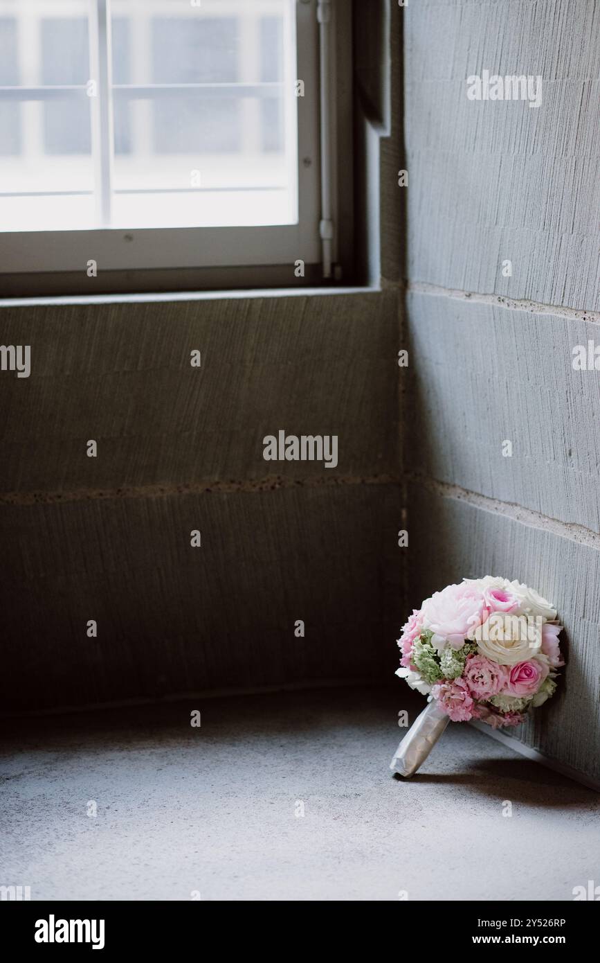 Bouquet nuziale di rose rosa e bianche vicino a una finestra in luce soffusa Foto Stock