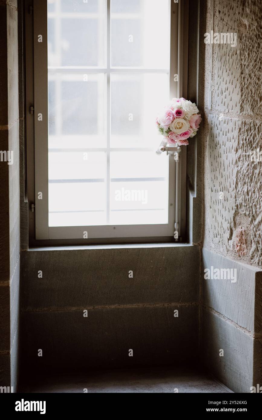 Bouquet nuziale di rose rosa e bianche vicino a una finestra in luce soffusa. Foto Stock