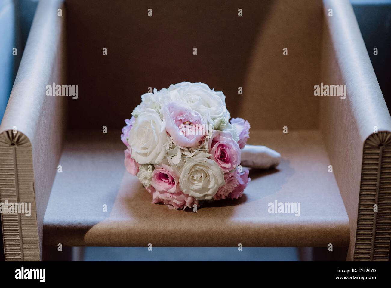 Bouquet nuziale con rose rosa e bianche su una sedia di cartone. Foto Stock