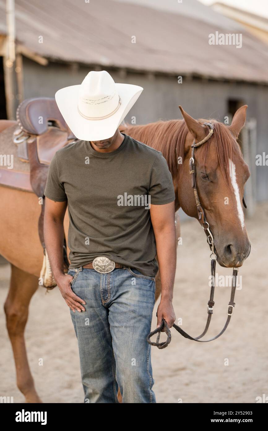 Uomo che guarda in basso mentre guida un cavallo Foto Stock