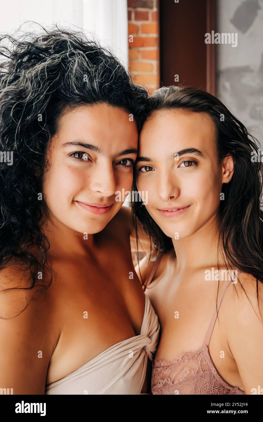 Due donne con sorrisi morbidi condividono un abbraccio intimo e intimo Foto Stock