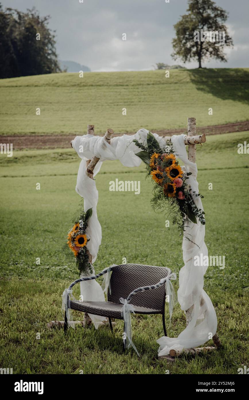 Arco nuziale all'aperto con girasoli e panca, in un campo di campagna Foto Stock