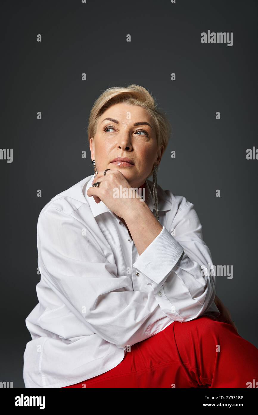 Una donna elegante in un abbigliamento elegante riflette le idee con un'espressione contemplativa. Foto Stock