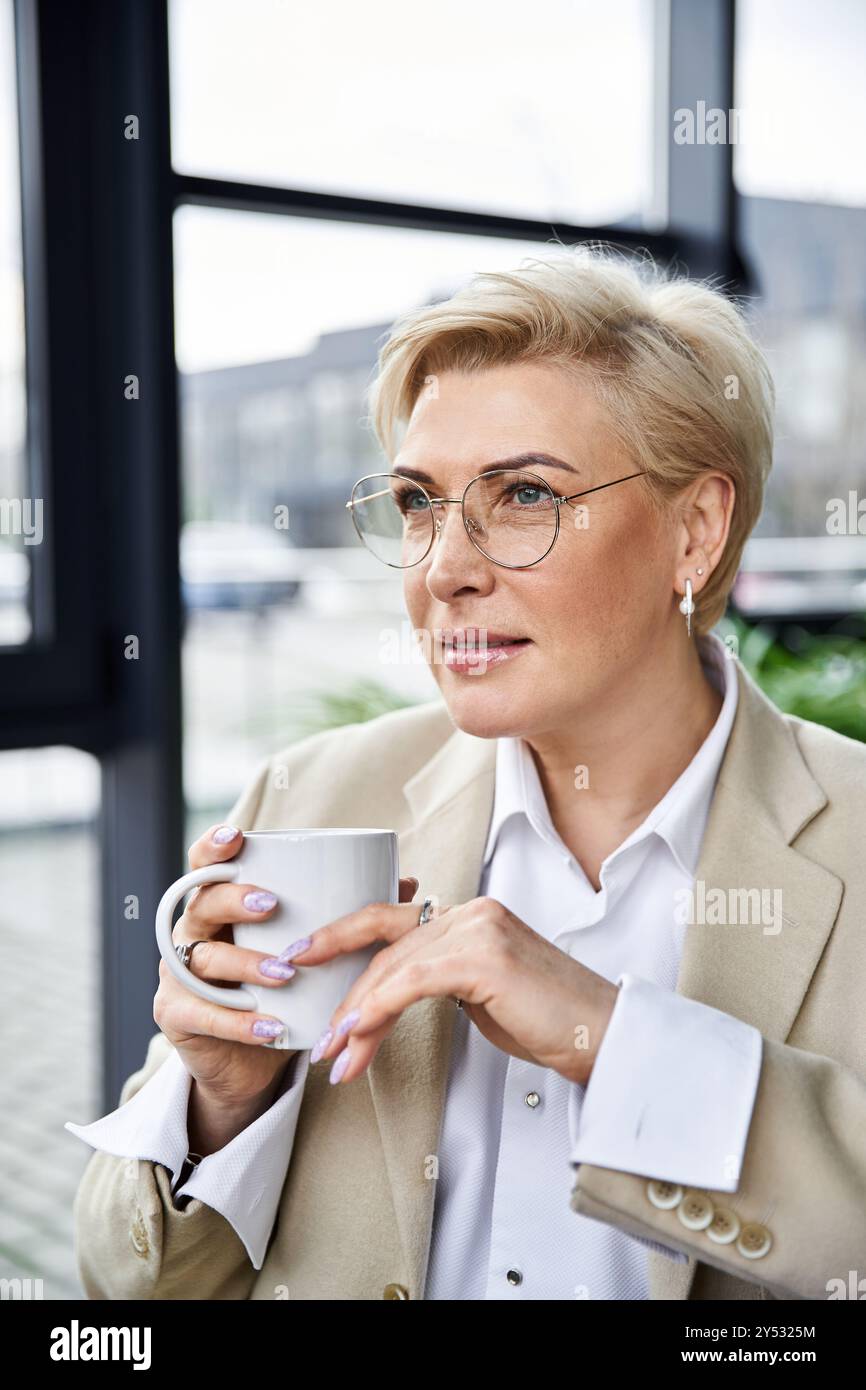 Una donna sofisticata sorseggia il suo caffè con cura, vestito elegantemente mentre si rilassa. Foto Stock