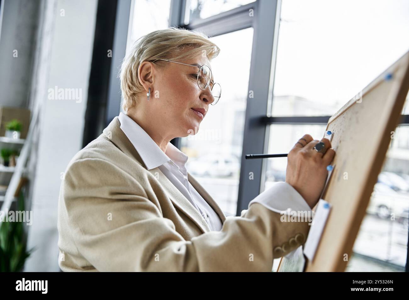 Una donna sofisticata con un abbigliamento elegante si ispira a una grande tavola, dando prova di creatività. Foto Stock