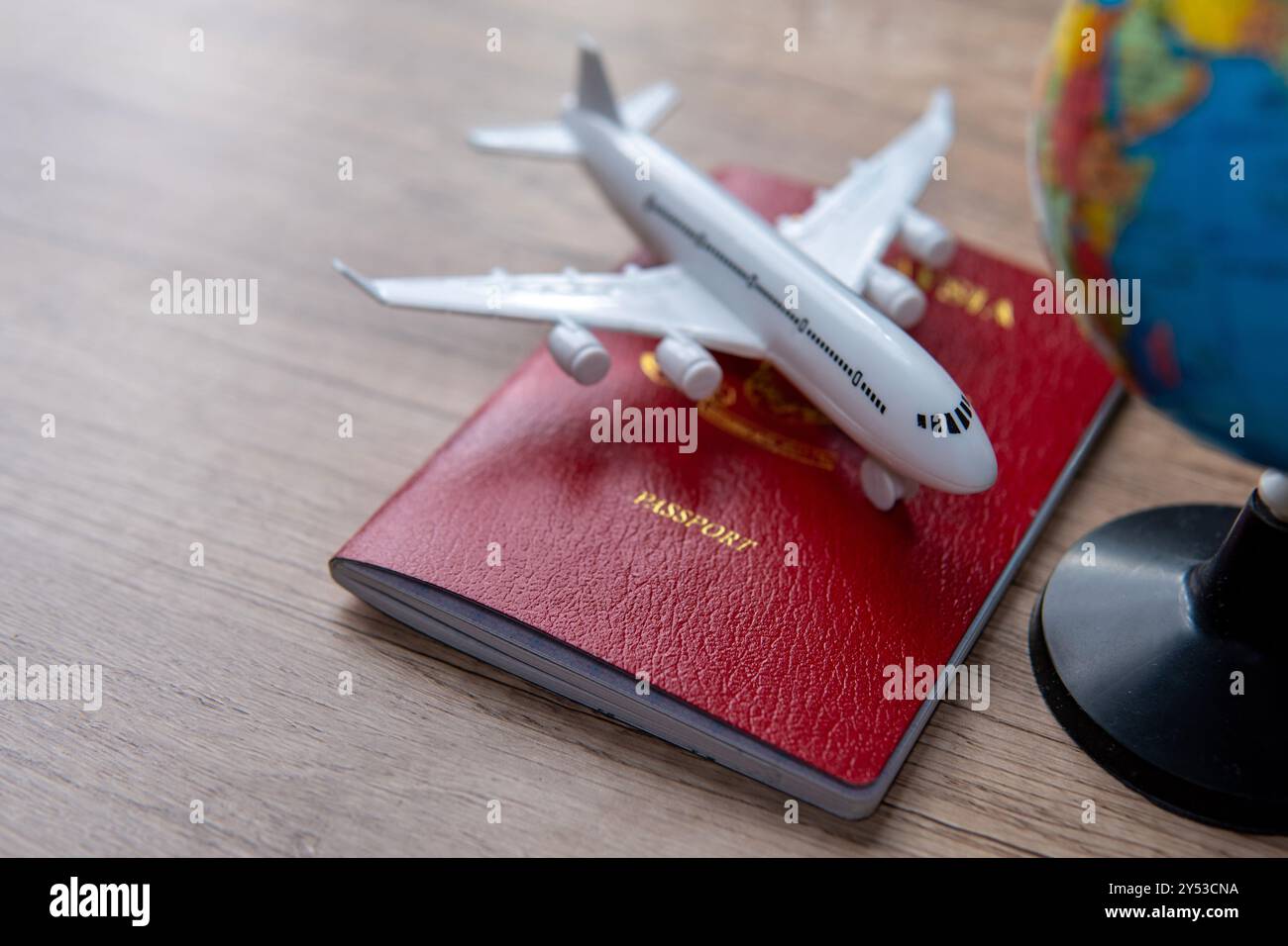 Un piccolo modellino di aereo sopra un passaporto e accanto a un piccolo globo. Copia spazio per il testo. Viaggi, collegamenti globali e viaggi internazionali Foto Stock