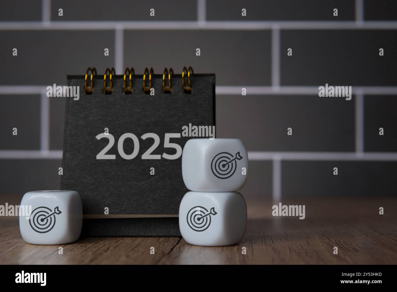 calendario da tavolo 2025 e dadi bianchi con l'icona della bacheca bersaglio. Risoluzione, obiettivo e concetto di obiettivi per l'anno nuovo. Foto Stock