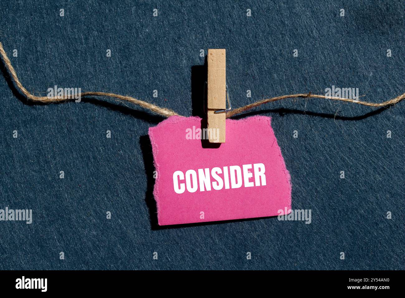 Considerare il messaggio scritto su un pezzo di carta rosa strappato con sfondo grigio. Simbolo concettuale da considerare. Copia spazio. Foto Stock