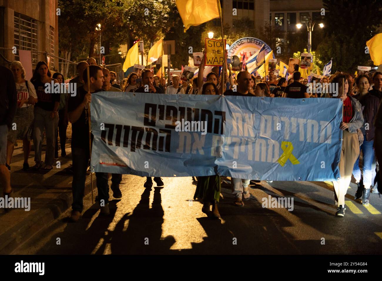 I manifestanti marciano per le strade di Gerusalemme di notte con segnali che chiedono la fine della guerra di Gaza e il rilascio degli ostaggi Foto Stock