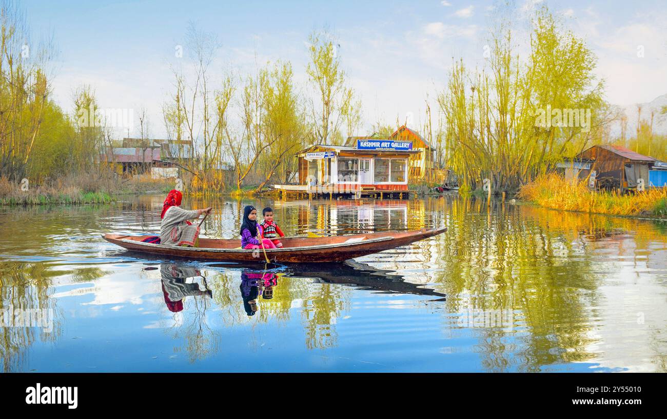 L'immagine mostra una scena sul lago dal, con una donna che canta su una barca che trasporta due bambini, circondata da case galleggianti e dai riflessi vibranti nell'acqua. Foto Stock