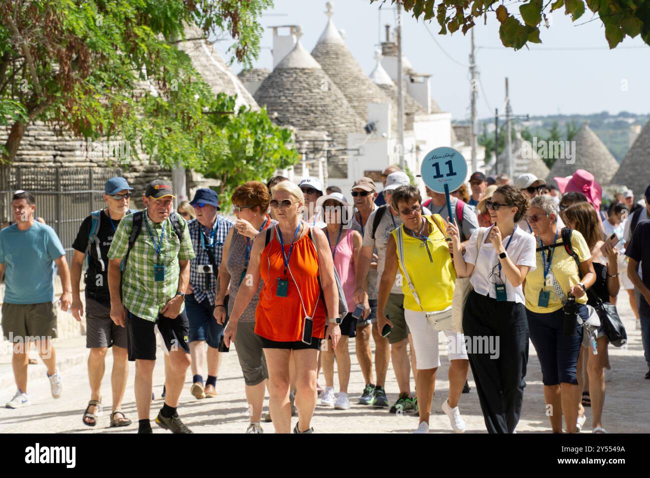 Grande gruppo di turisti che seguono la guida turistica attraverso le strade di Alberobello Italia possibile esempio di over Tourism Foto Stock