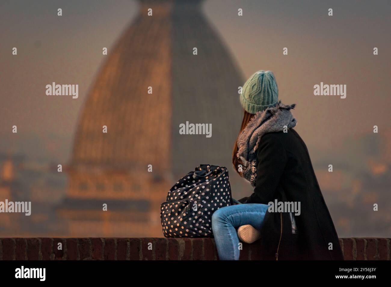 Paesaggistico - Una giovane ragazza immersa nei suoi pensieri di fronte a un romantico paesaggio torinese con l'iconica Mole Antonelliana. Foto Stock