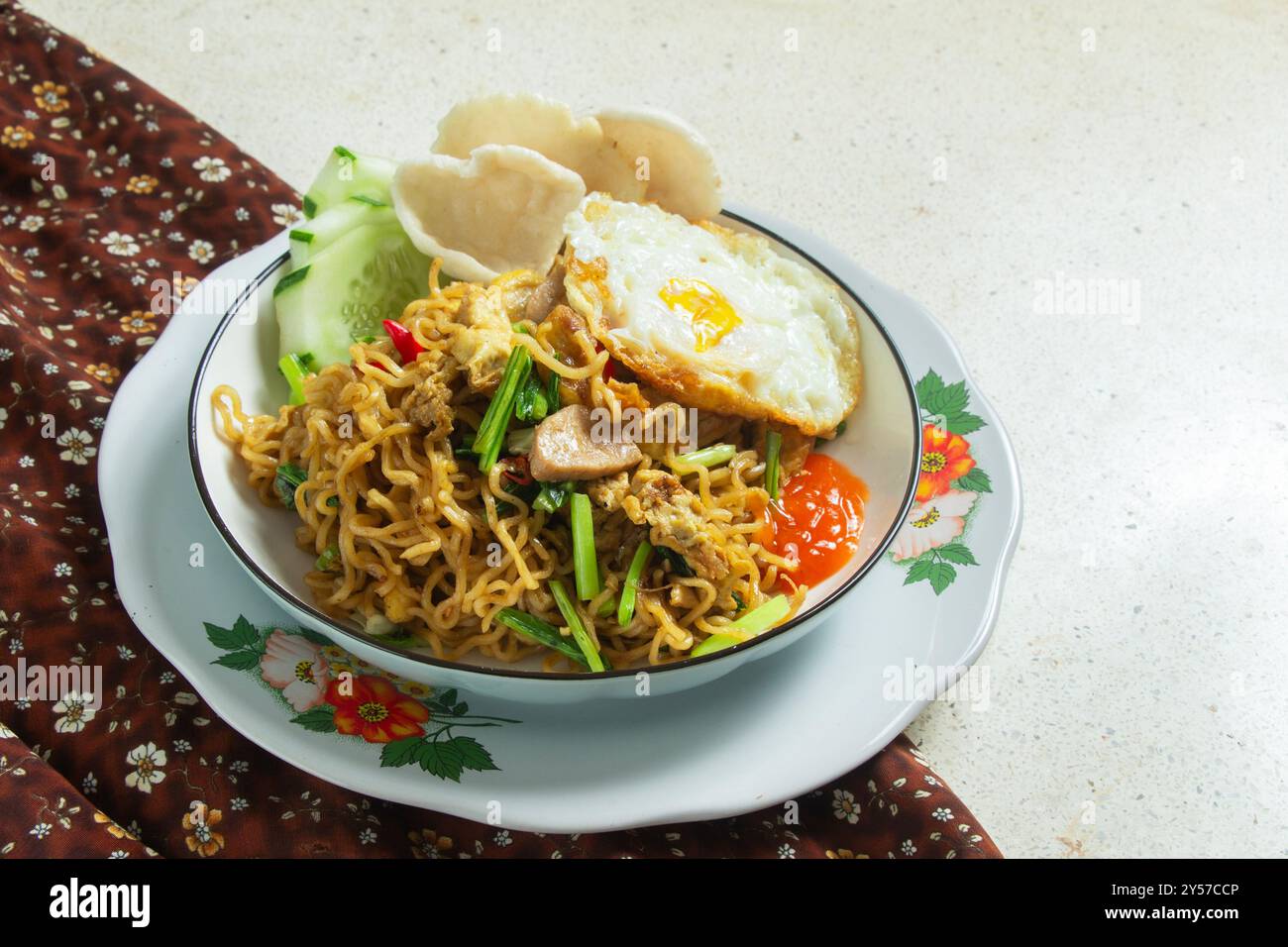Spaghetti fritti su un piatto bianco rotondo con un panno marrone su un tavolo di marmo bianco, cibo indonesiano, spazio negativo Foto Stock