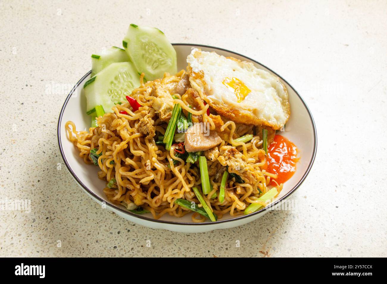 Mei fritti con condimento rotondo all'uovo, fette di cetriolo, salsa, sfondo da tavolo con consistenza in marmo bianco, cibo indonesiano Foto Stock