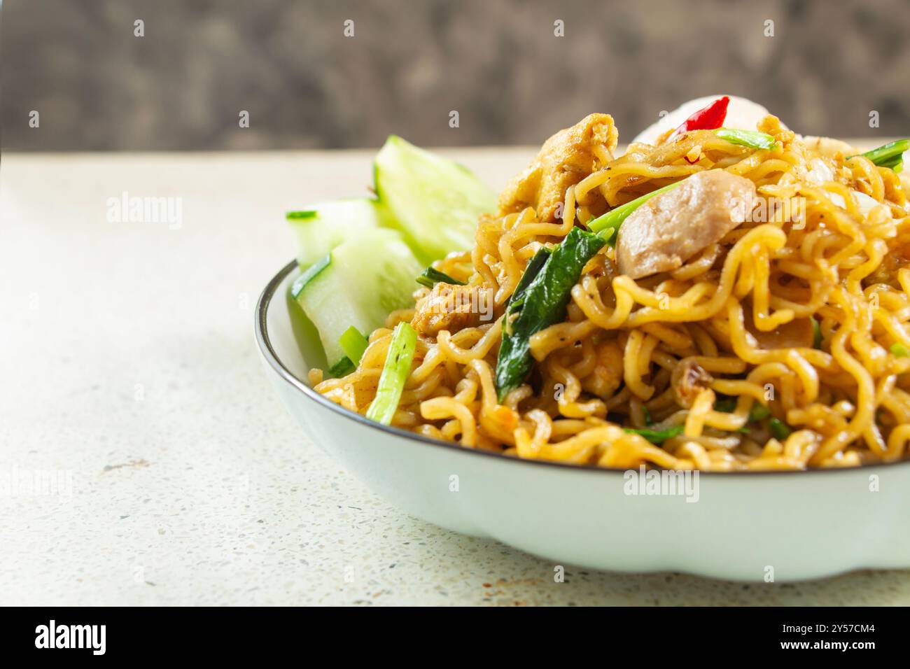primo piano di spaghetti fritti ripieni di polpette, uova fritte, cetrioli e verdure su un tavolo di marmo bianco, spazio negativo Foto Stock