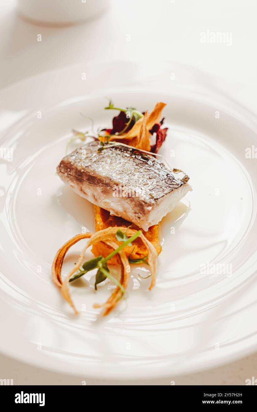 Il branzino è una tipica portata principale sui tavoli italiani. Ecco una placcatura da buongustai. Foto Stock