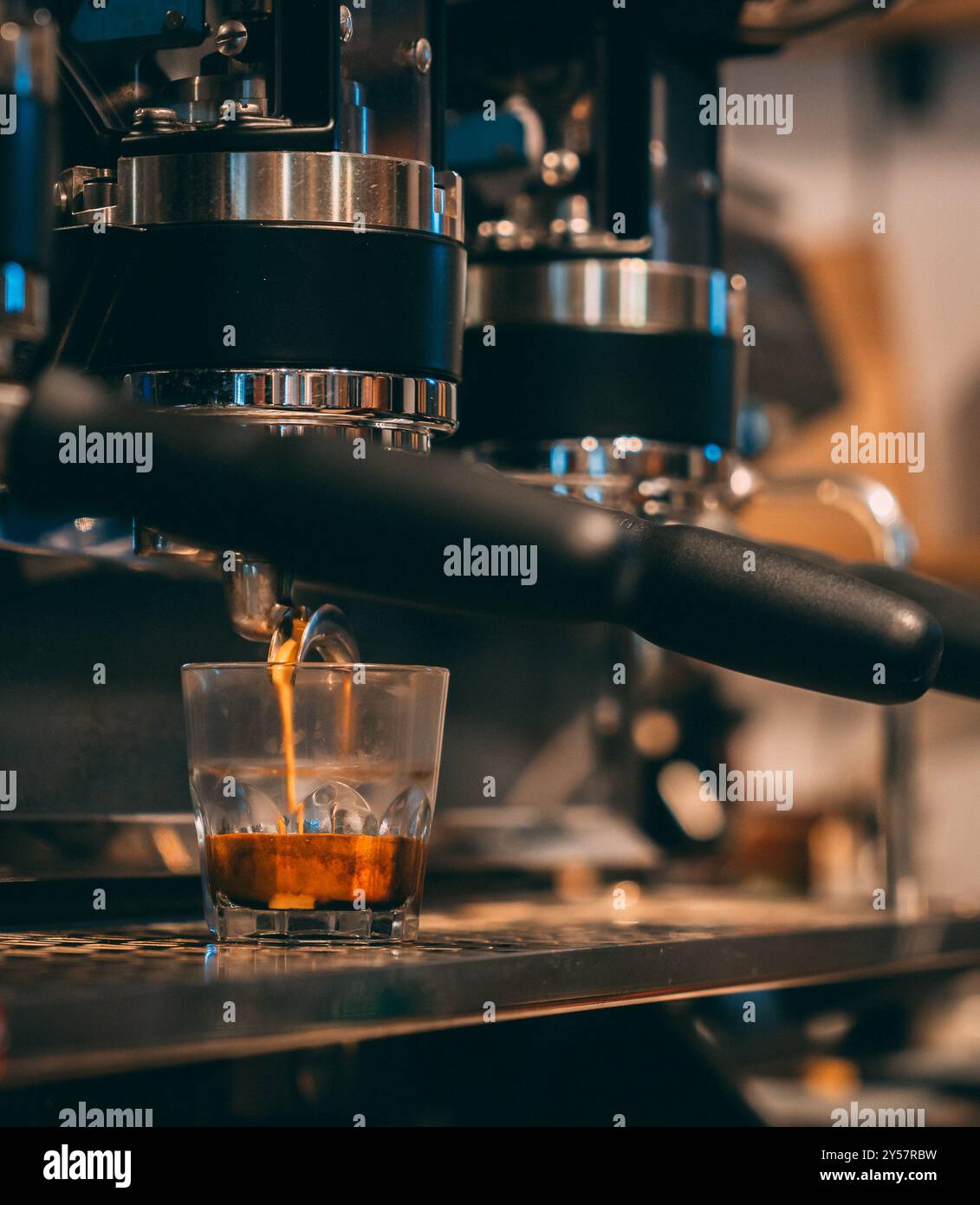Espresso che fuoriesce da un portafiltro in una macchina per il caffè in un bicchiere. Foto Stock