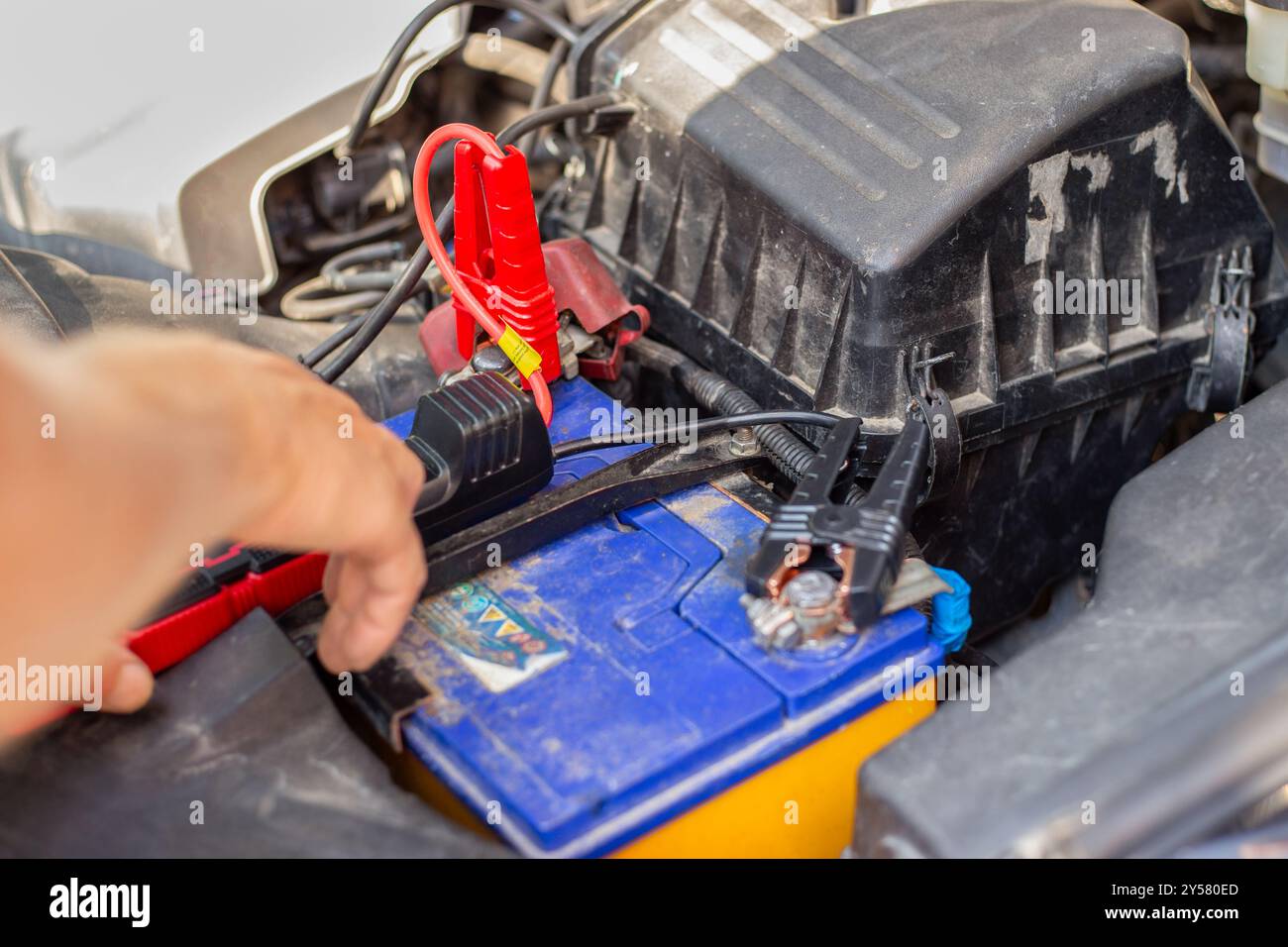 Il conducente carica la batteria scarica della vettura con un motorino di avviamento ausiliario. Batteria scarica. Foto Stock