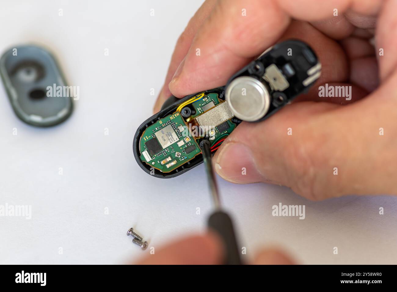 Londra. REGNO UNITO- 09.18.2024. Un tecnico che ripara una cuffia wireless utilizzando un cacciavite. Foto Stock