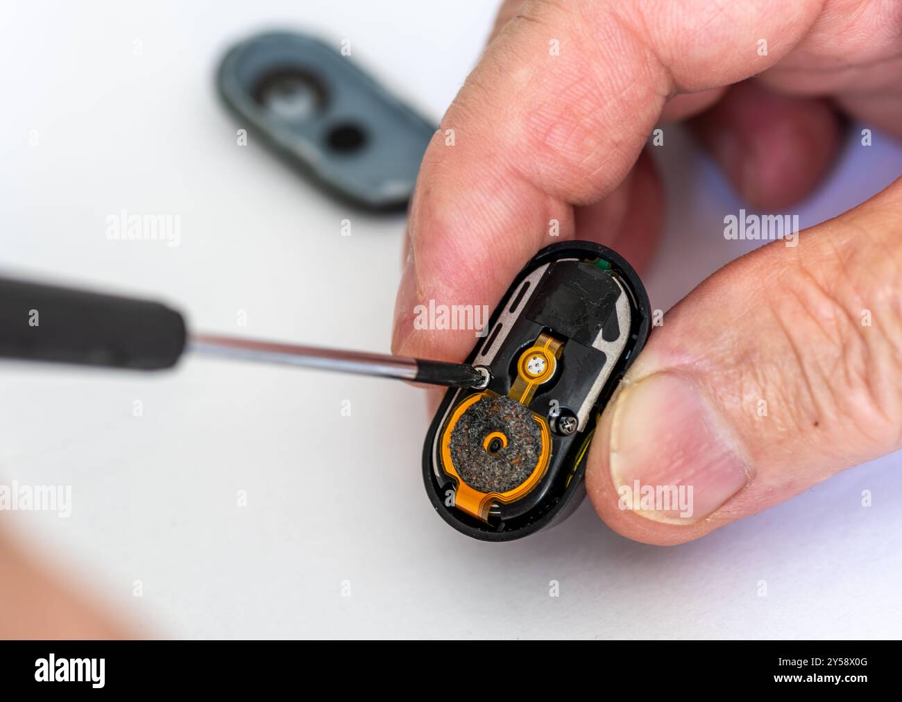 Primo piano di un tecnico che ripara una cuffia wireless utilizzando un cacciavite. Foto Stock