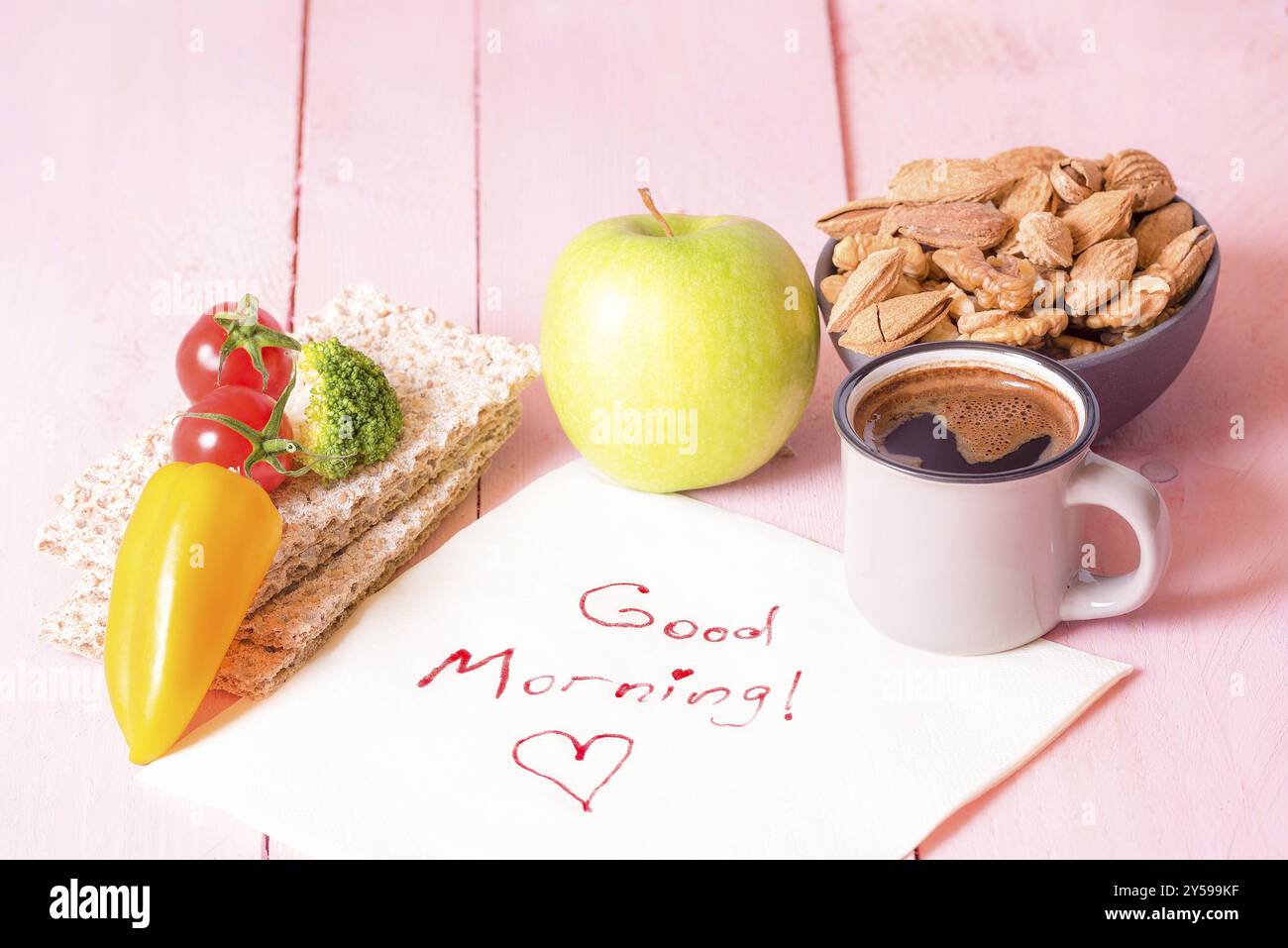 Colazione nutriente con pane croccante, verdure, frutta, una ciotola di mandorle, noci, una tazza di caffè su un tovagliolo con le parole del buon mattino, su un pi Foto Stock