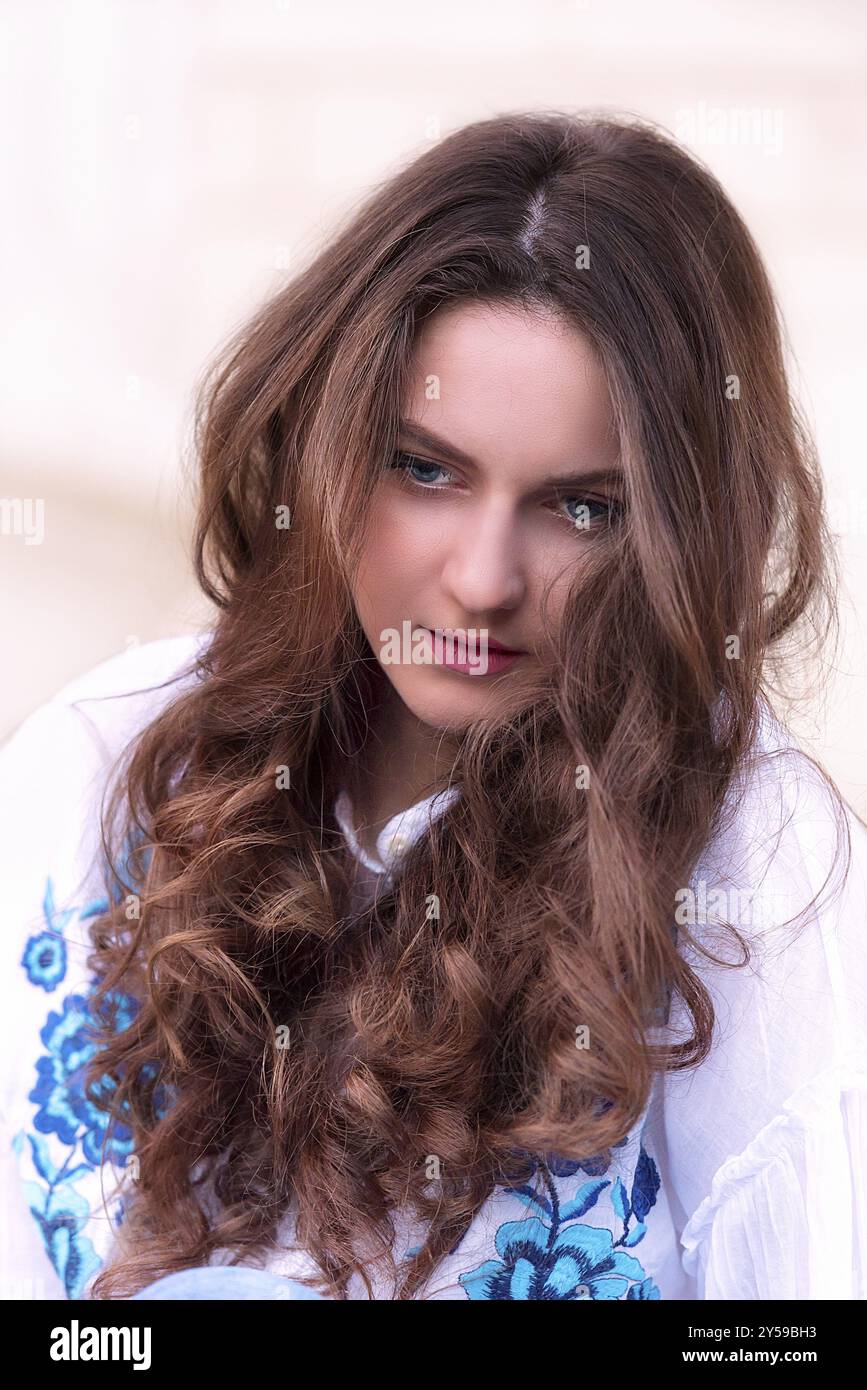 Ritratto di una giovane ragazza caucasica con capelli castani e occhi blu, con un'espressione meditativa sul suo viso Foto Stock