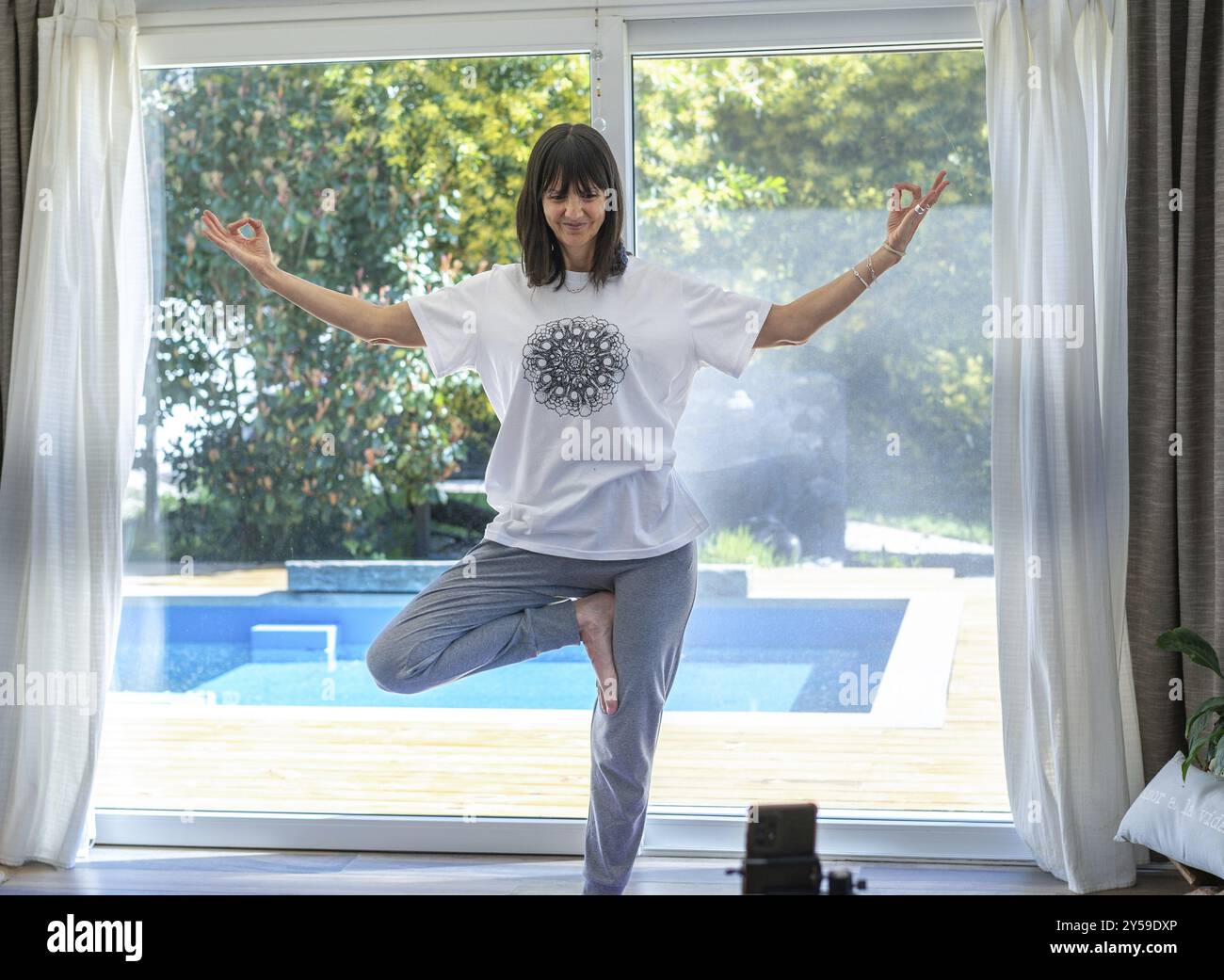 Istruttore di yoga a casa che filma contenuti coinvolgenti per i suoi seguaci sui social media Foto Stock