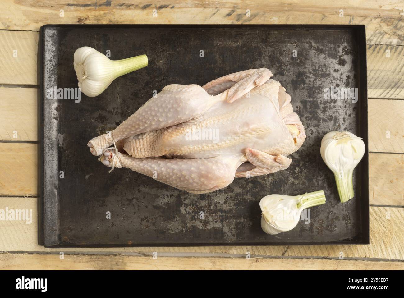 Pollo arrosto preparato per arrostire con aglio giovane su un vassoio da forno Foto Stock