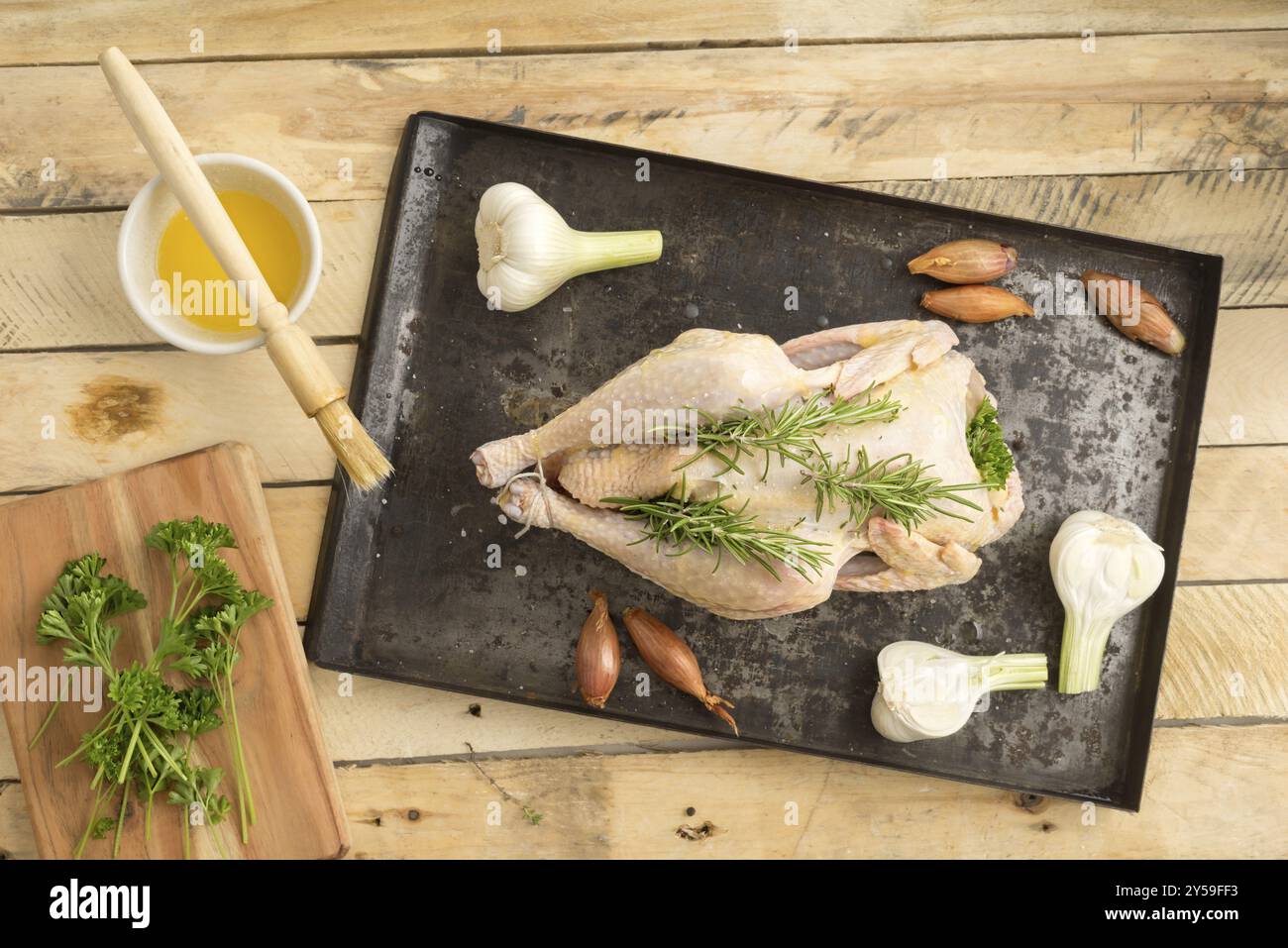 Pollo arrosto preparato per arrostire con aglio giovane, scalogni, prezzemolo e olio d'oliva su un vassoio da forno Foto Stock