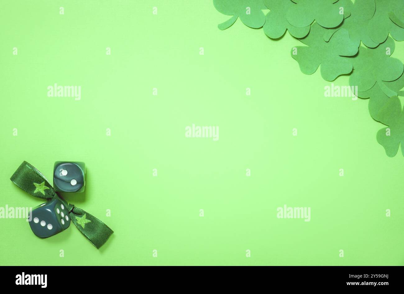 Concetto di San Patrizio con tritatutto di carta verde scuro in un angolo e un papillon e dadi nell'altro, posizionati su un foglio di carta verde chiaro vuoto Foto Stock