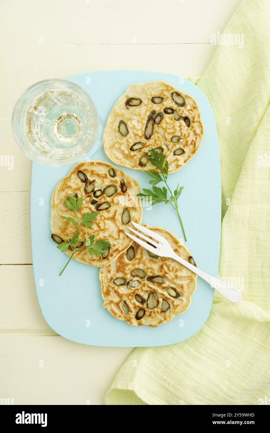 Frittelle con asparagi viola su un piatto color turchese Foto Stock