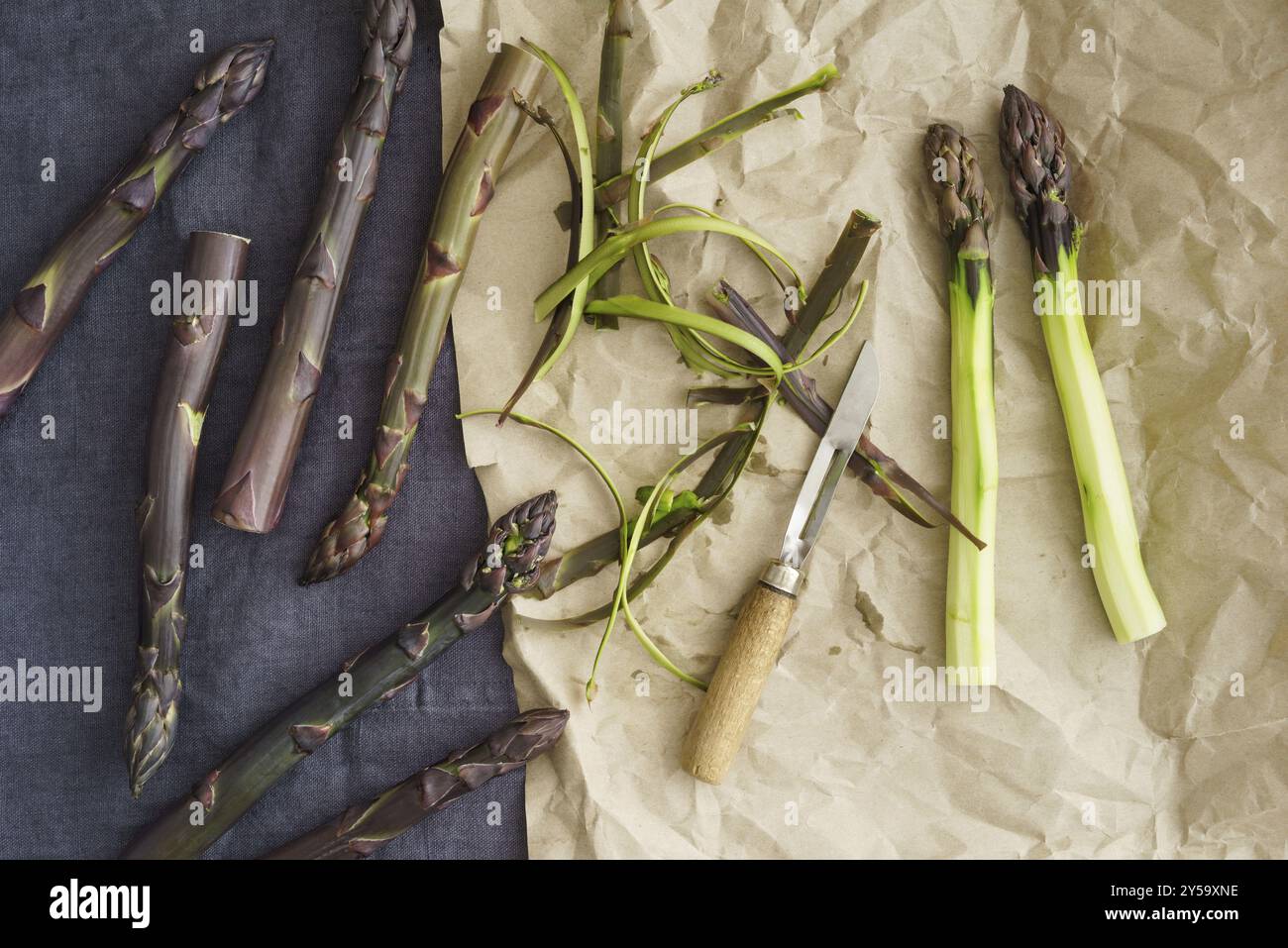 Asparagi viola freschi su carta con un vecchio coltello da cucina Foto Stock
