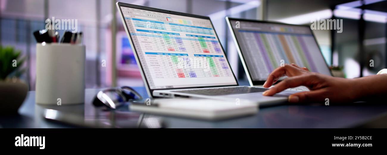 Calcolo di conti medici elettronici e codici in un ufficio nero utilizzando un foglio di calcolo sullo schermo di un computer. Foto Stock