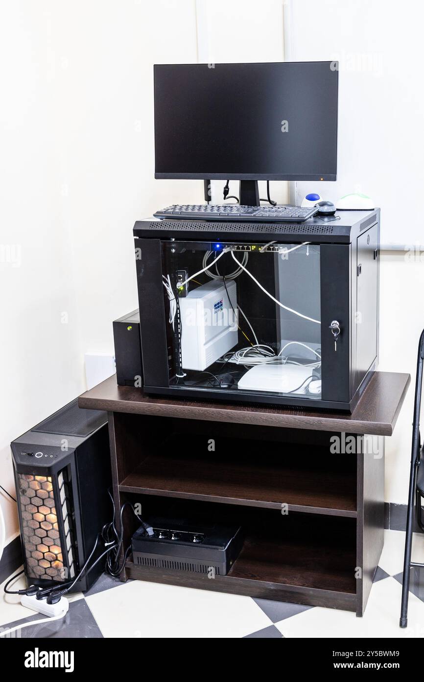 stativo in legno nell'angolo della sala ufficio con server, router, monitor per computer, gruppo di continuità Foto Stock