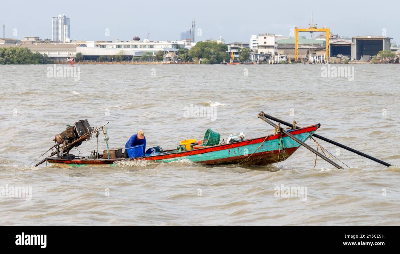 SAMUT PRAKAN, THAILANDIA, 21 GIUGNO 2024, pescatore su una barca alla foce del fiume Chao Phraya Foto Stock