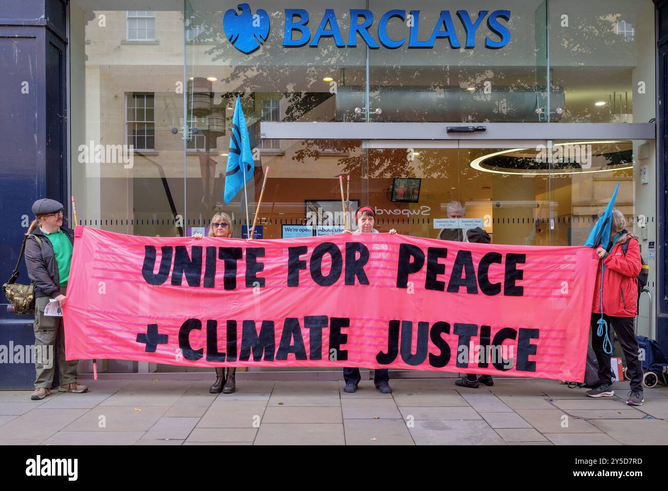 Bath, Regno Unito. 21 settembre 2024. I manifestanti sono ritratti fuori dalla Barclays Bank mentre prendono parte a una marcia di protesta attraverso il centro di Bath. Barclays è stata criticata per i suoi investimenti in società che forniscono armi. La protesta "combattere il cambiamento climatico - non alimentare la guerra” è stata organizzata da Extinction Rebellion Bath e dal gruppo "Stop War" di Bath ed è stata organizzata per evidenziare il fatto che il Regno Unito spende sette volte più in armi che in relazione al cambiamento climatico. Crediti: Lynchpics/Alamy Live News Foto Stock