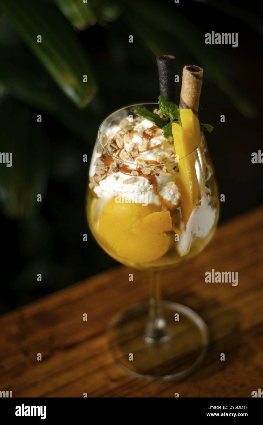 Mango biologico e gelato tropicale con frutta della passione in bicchiere di vino Foto Stock
