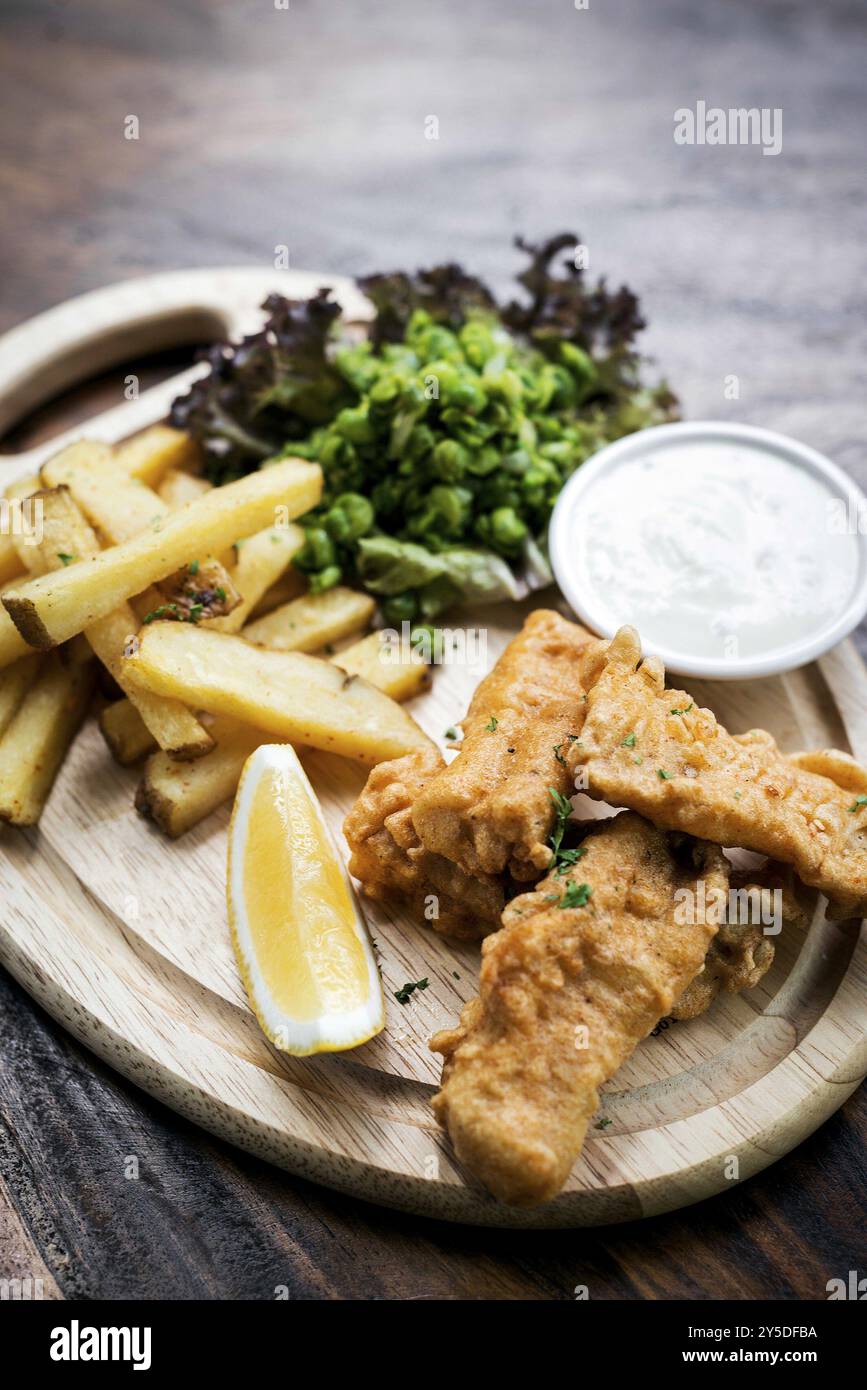 Pesce e patatine tradizionali con piselli e salsa di tartaro Foto Stock