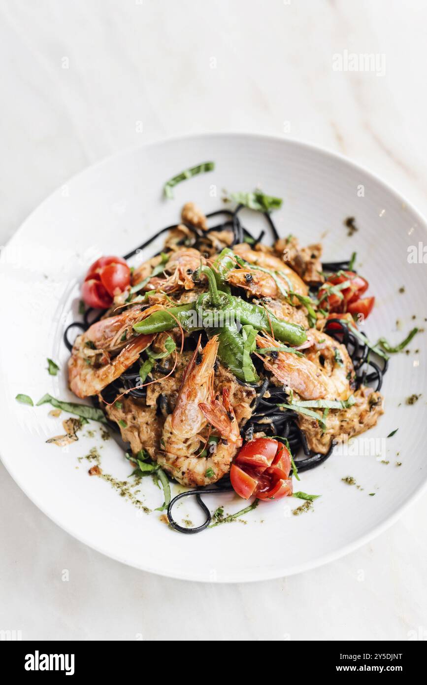 Piatti gourmet di gamberi alla griglia e verdure su pasta al nero di calamaro Foto Stock
