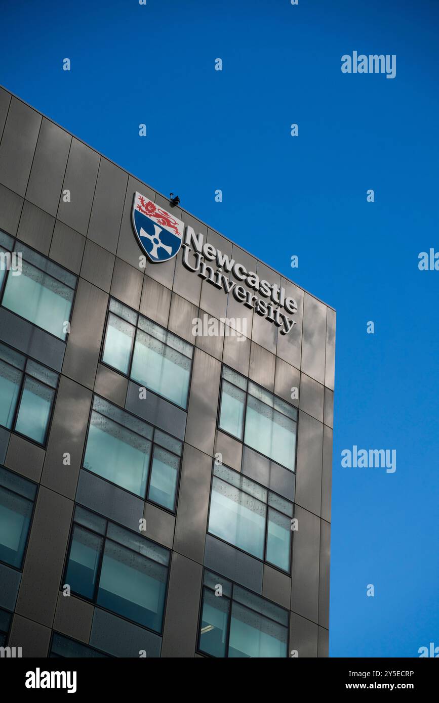 Vista generale di un edificio della Newcastle University con il logo e lo stemma della Newcastle University mostrati come un cartello in una giornata di sole. Foto Stock