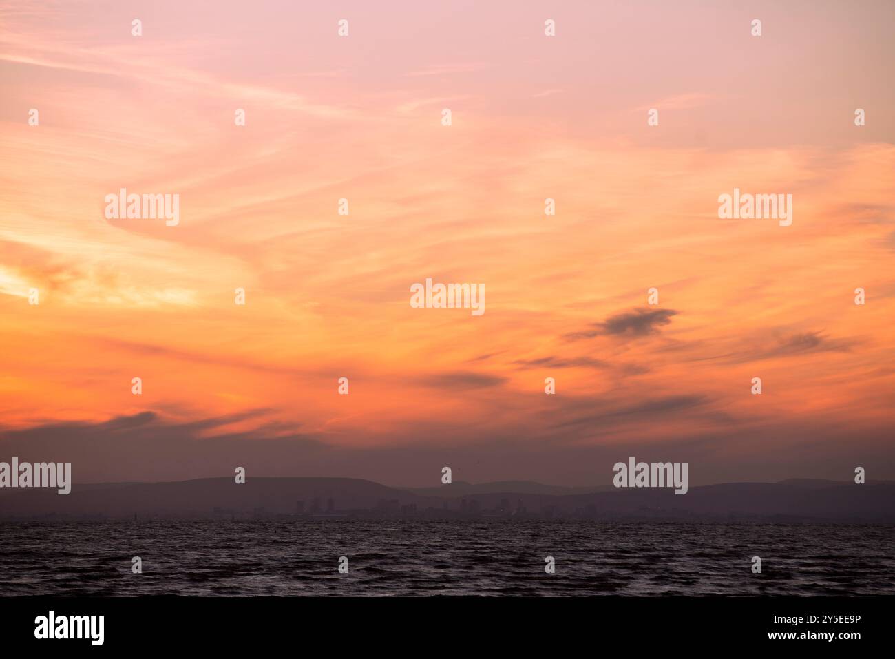 Il sole tramonta sul Galles visto dalla spiaggia di Weston-super-Mare nel Somerset. Foto Stock