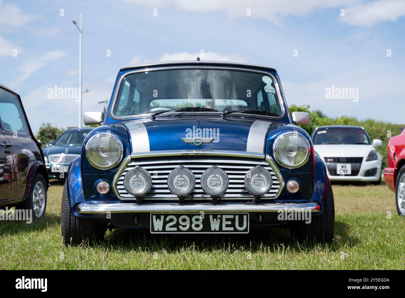 Una Mini Cooper blu scuro con fendinebbia parcheggiata in una mostra di auto a Weston-super-Mare, nel Somerset settentrionale, in una giornata di sole. Il Mini è un modello di registrazione W, registrato nel 2000. Foto Stock