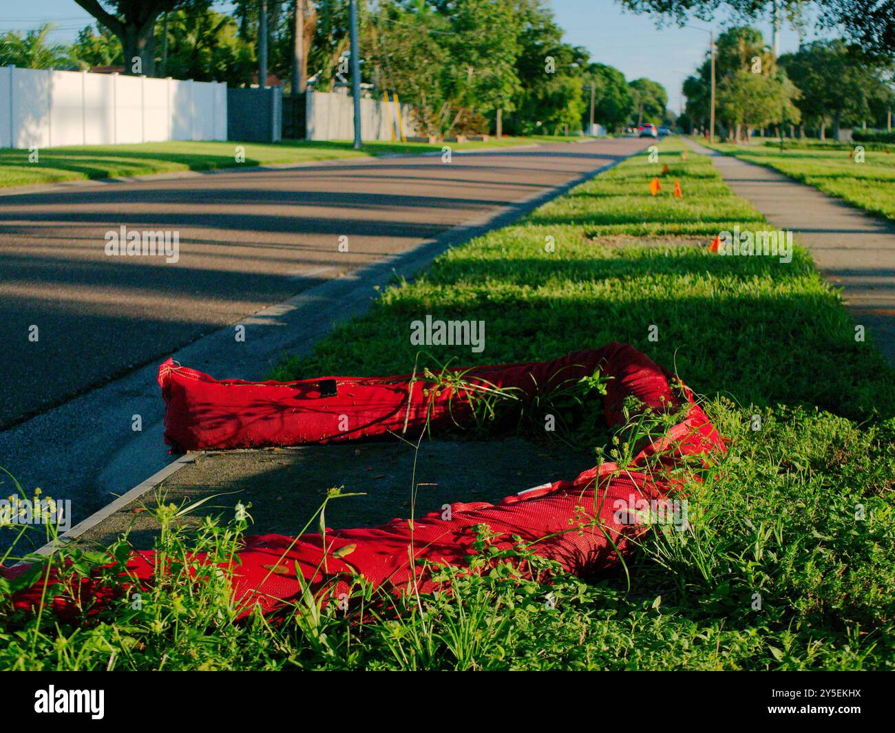 Barriere di protezione dell'ingresso dello scarico delle tempeste rosse intorno alla fogna sul lato della strada. Linee principali lungo marciapiede e strada. Progettato per intrappolare carichi pesanti Foto Stock