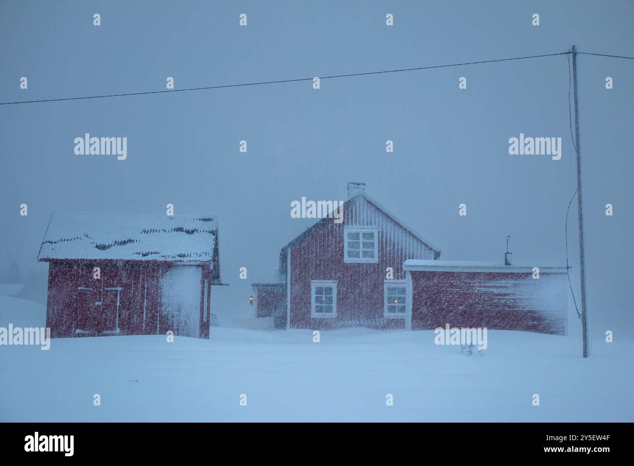 Case rosse svedesi e una linea elettrica in una delle tempeste di neve più forti del 2024, Hemavan, Svezia Foto Stock