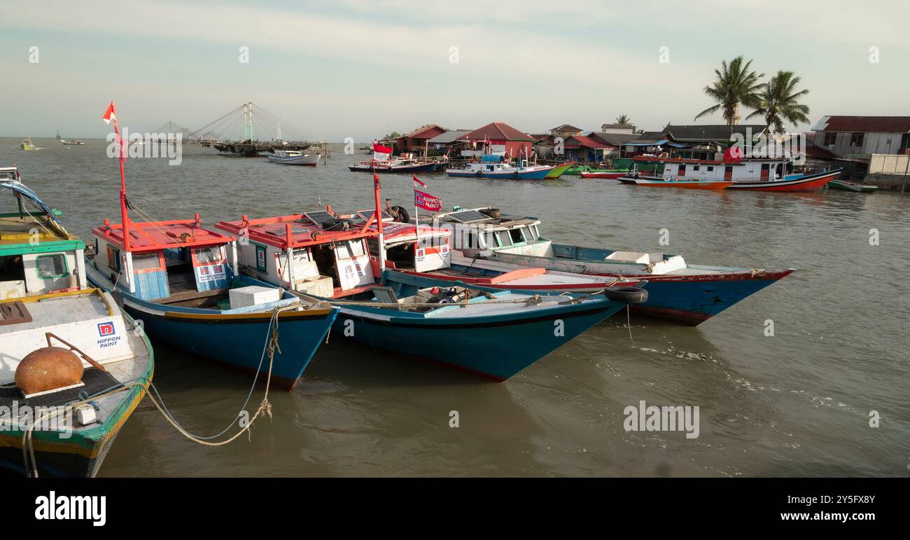 Balikpapan, Borneo Orientale, Indonesia. Un gruppo di barche è ormeggiato in un porto, alcune delle quali sono blu e rosse Foto Stock