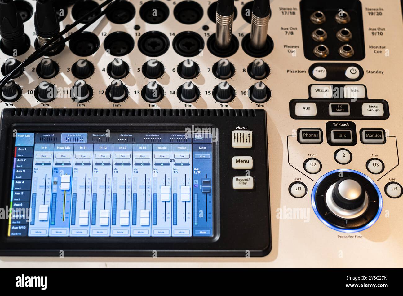 Vista ravvicinata di una console di missaggio audio professionale dotata di manopole, cursori e pulsanti. L'interfaccia digitale visualizza i livelli audio e. Foto Stock