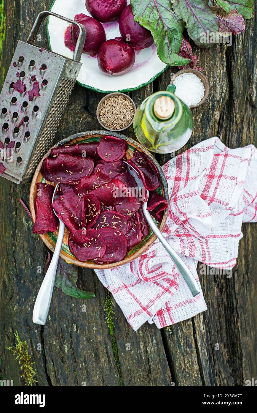 Ciotola di insalata di barbabietole fresche con olio e semi di cumino su un tavolo di legno in giardino Foto Stock