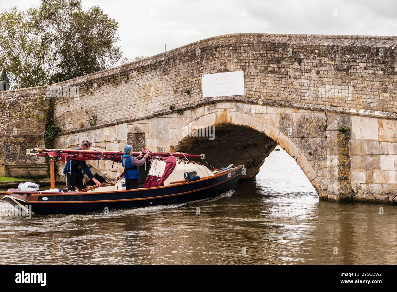 Barca a vela che passa sotto il basso vecchio ponte sul fiume Thurne nel Parco Nazionale di Norfolk Broads. Potter Heigham, Norfolk, East Anglia, Inghilterra, Regno Unito, Foto Stock